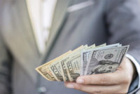 Businessman holding USD banknote for payment .US dollar is main and popular currency of exchange in the world. Investment and saving concept.